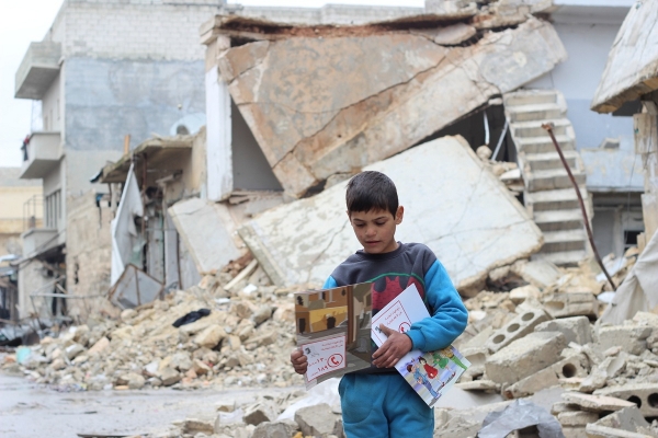 ▲폐허가 된 시리아에서 유니세프로부터 받은 불발탄 확인 안내 교재를 가지고 걸어가고 있다. 시리아 알레포 전역에 남아 있는 불발탄으로 어린이들이 생명을 위협받고 있다. 지난 12월 알레포 동부 지역에서 불발탄 사고로 어린이 6명이 사망하기도 했다. ⓒ유니세프 제공