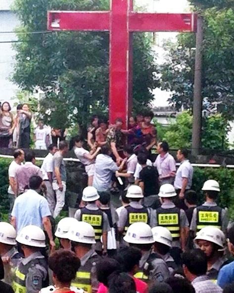 지난 2015년 7월 22일 저장성 원저우 룽완 지역의 쌍촌교회 여성 성도들이 정부의 십자가 철거에 항의하여 자신을 십자가에 묶었으나 공무원들에 의해 강제로 끌어내려지고 있다. ⓒ차이나에이드