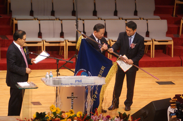 신임회장 이만호 목사(가운데)가 직전회장 김홍석 목사(우)로부터 교협기를 인계받고 있다.