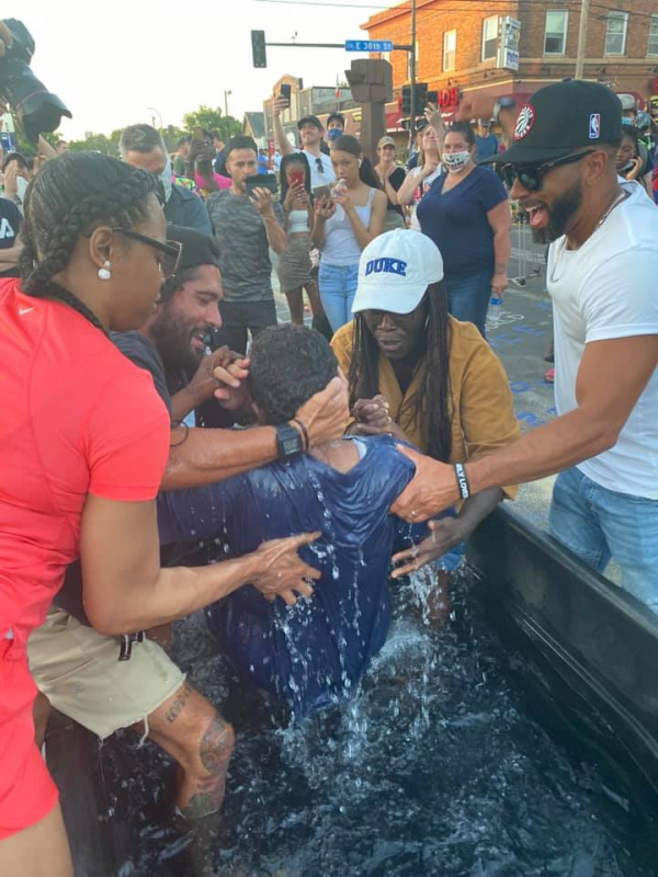 조지 플로이드가 사망한 거리에서 시위 참가자 중 한 사람이 침례를 받고 있다.