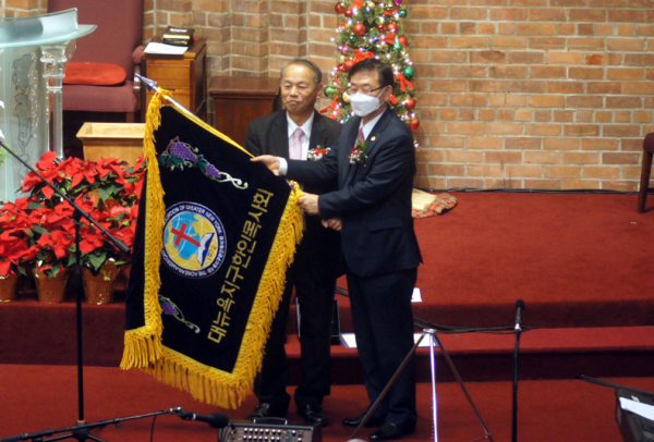 이준성 목사(좌)가 김진화 목사에게 뉴욕목사회기를 전달했다.