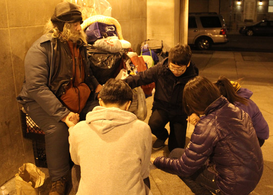 영하의 날씨에 거리에서 잠을 자는 노숙자들에게 음식을 나누며 기도해 주는 청소년 봉사자들.