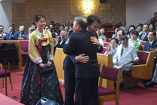 교회대표 장석면 장로와 2대 담임 강기성 목사가 서약 후 서로 포옹하고 있다.
