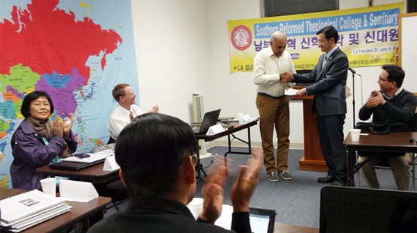 이 학교 LA캠퍼스 책임자이면서 말씀새로운교회를 담임하고 있는 김회창 박사가 아룬 다스 목사에게 장학금을 전달하고 있다. 