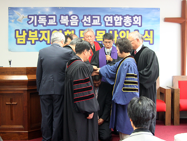 기독교복음선교연합총회 목사안수식에서 안수위원들이 김진규 전도사에게 안수하고 있다.