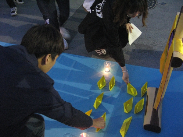신학생들이 세월호 참사와 희생자들을 기억하면서 노란종이배를 접어 놓고 있다.